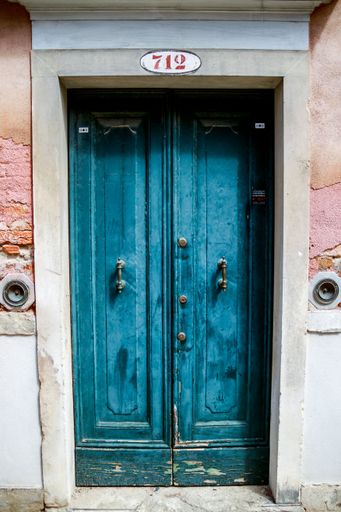 A vertical shot of the ancient blue door on the street of Venice, Italy