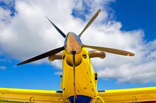A low angle shot of propeller on a yellow aircraft