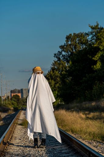 A ghost standing on the train tracks in the countryside - Halloween concept