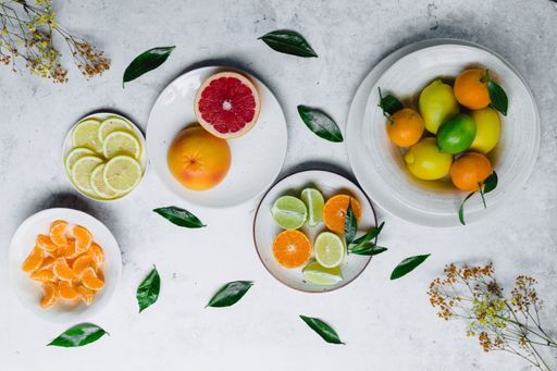 The flat lay of various citruses on white plates