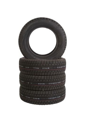 A vertical shot of a stack of car tires isolated on a white background