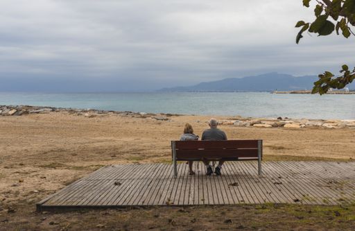 A middle-aged couple sitting on a bench and admiring the sea