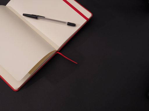 A closeup shot of an open and empty notebook for text with a pen isolated on dark background