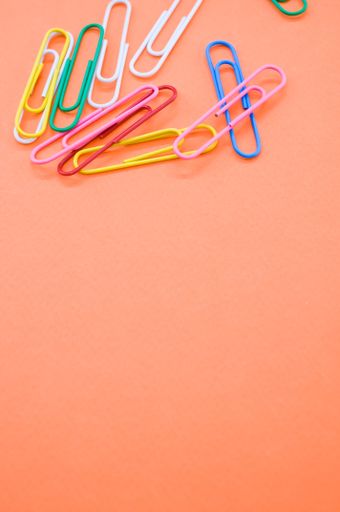 A closeup shot of colorful paper clips on an orange background