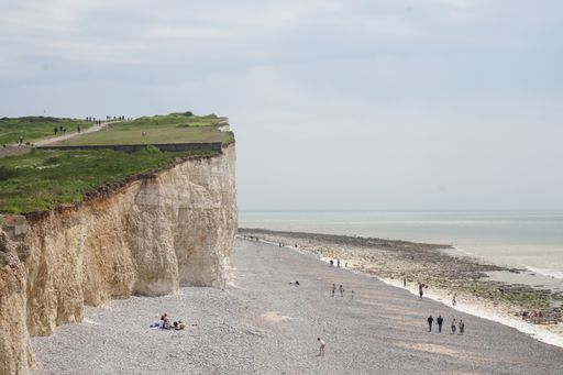A sandy crowded coastline in South Downs National Park, Pulborough, UK with chalk cliff
