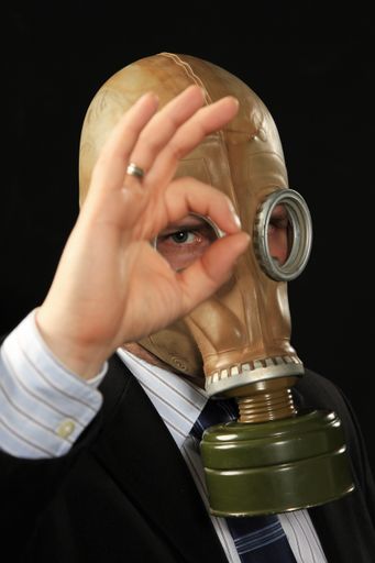 A vertical closeup shot of a man wearing a gas mask in a suit
