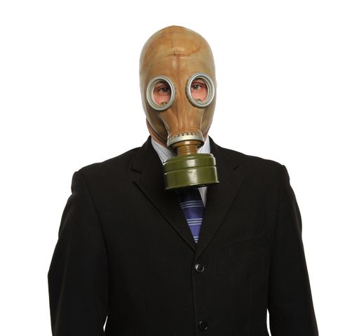 A vertical shot of a man in a suit wearing a gas mask