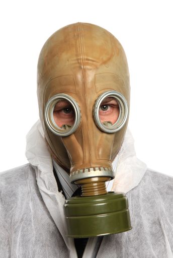A vertical shot of a male wearing a protective suit and a gas mask