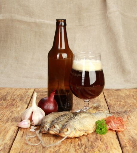 A vertical shot of dried fish and beer on a wooden table
