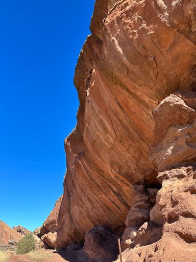 A vertical shot of a big red cliff in a desert against the clear blue sky during the daytime