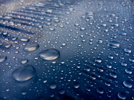 A high angle macro shot of water drops on a blue surface for wallpaper/background