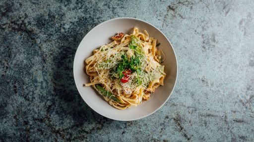 A top view of delicious pasta topped with basil, cheese and tomato