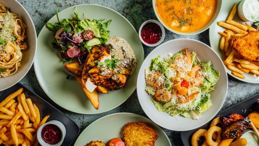 A top view of different meals with Cesar salad, french fries and cheese nuggets