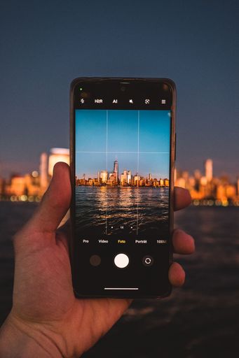 A person taking a picture of New York skyline with a phone at night