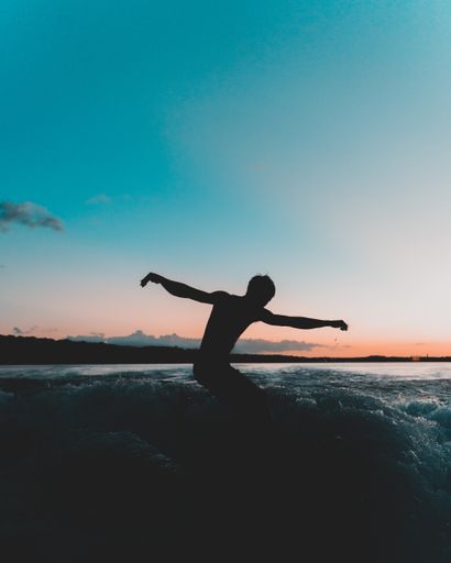 A silhouette shot of a surfer enjoying the waves during sunset
