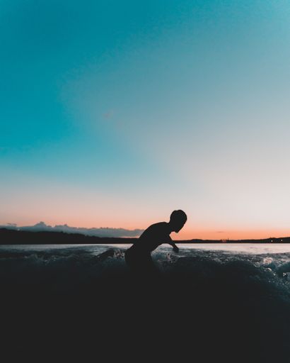 A silhouette shot of a surfer enjoying the waves during sunset