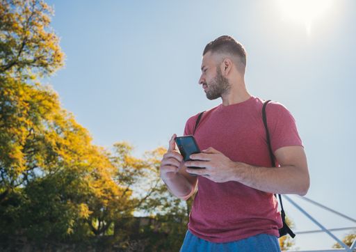 A low angle shot of a young man checking his phone before training