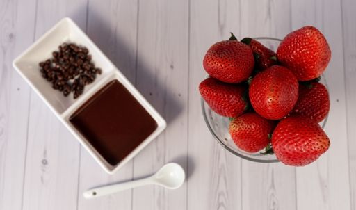 A top view of strawberries with melted chocolate on a white wooden surface
