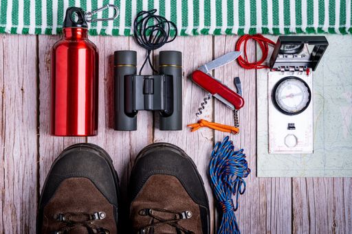 The flat lay of hiking equipment, essential tools on the wooden surface