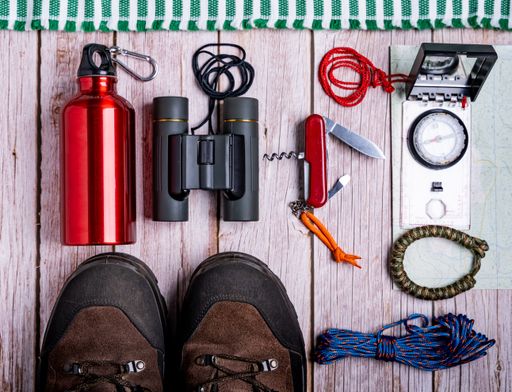 The flat lay of hiking equipment, essential tools on the wooden table
