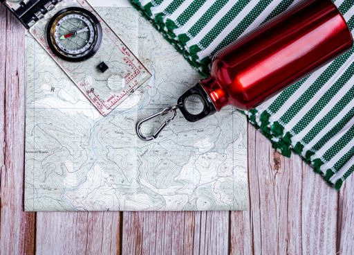 The flat lay of hiking equipment - map, bottle, and compass