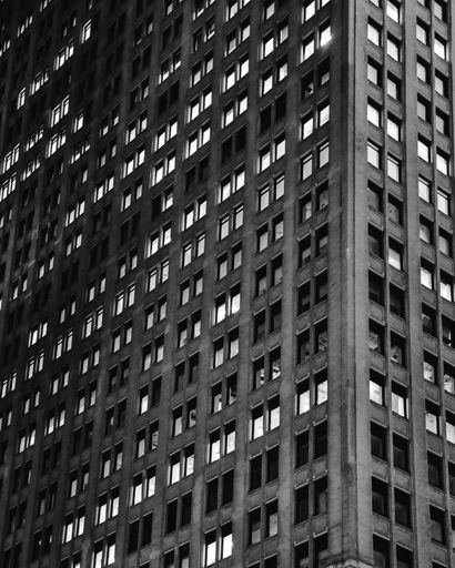 A vertical low angle grayscale shot of a tall office building