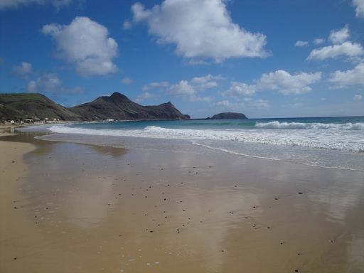 A beautiful shot of a seashore with mountains under a bright cloudy sky on Porto Santo Island