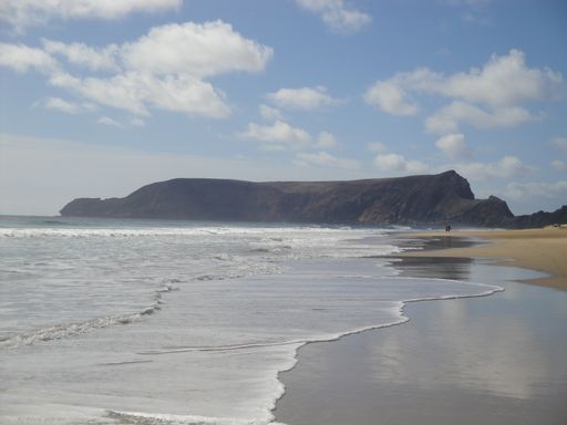 A beautiful shot of a seashore with mountains under a bright cloudy sky on Porto Santo Island