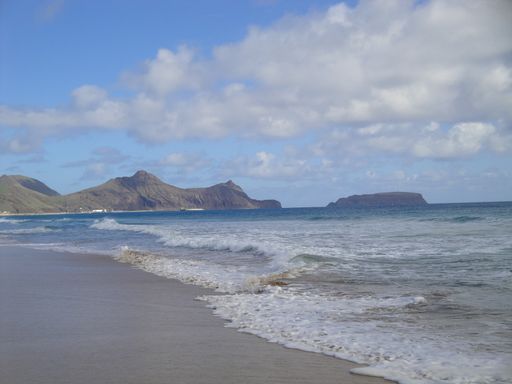 A beautiful shot of a seashore with mountains under a bright cloudy sky on Porto Santo Island