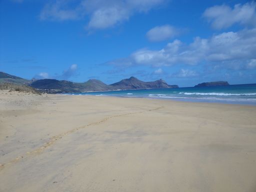 A beautiful shot of a seashore with mountains under a bright cloudy sky on Porto Santo Island