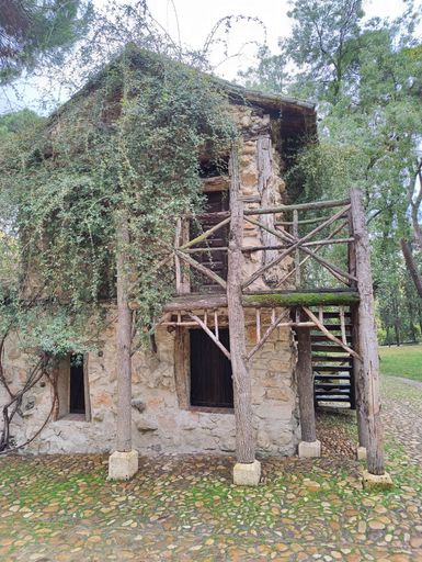 A vertical shot of the abandoned old stone building in the park surrounded by trees during the daytime