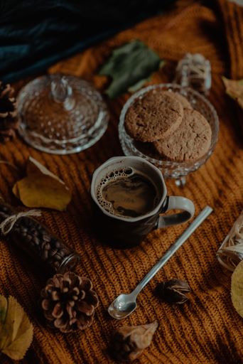 A vertical shot of tasty cookies and coffee in an autumn decoration set