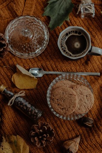 A vertical high angle shot of tasty cookies and coffee in an autumn decoration set