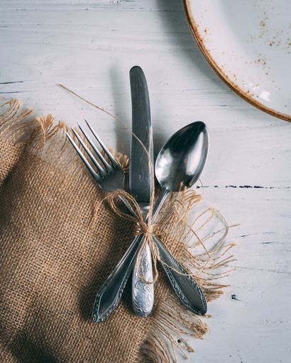 The fork, knife, and spoon tied in a bow on the wooden table