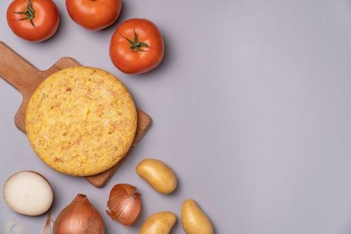 a flat lay of casserole potatoes and tomatoes on a gray background