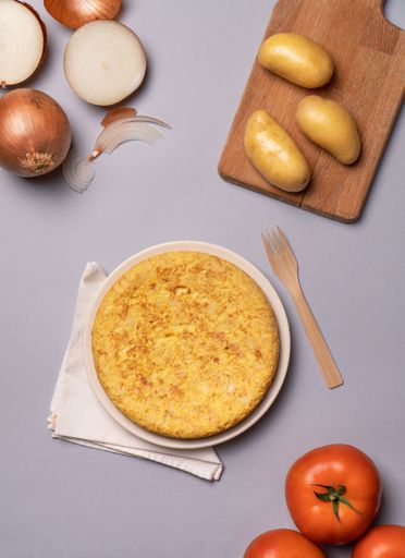 a flat lay of casserole potatoes and tomatoes on a gray background