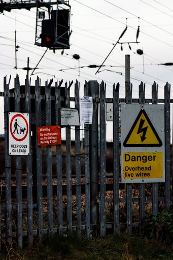 Red and yellow warning signs prohibiting trespassing and instructing to keep dogs on leads in a forbidden area