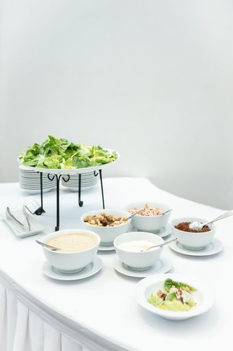 A vertical shot of different salads, snacks, sauces in white bowls  prepared for a banquet