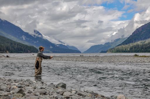 A Caucasian man standing in the Ralph River fishing with the scenic landscape in the background