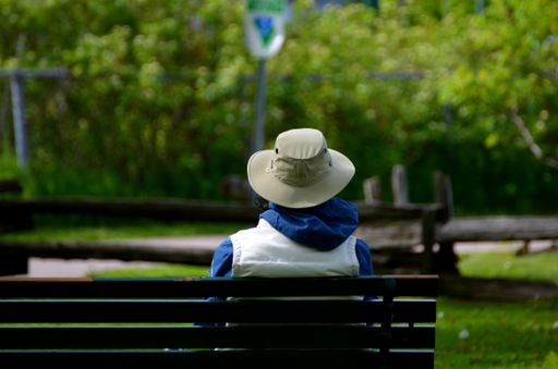 A person sitting alone on a park bench enjoying the fresh air and morning sun