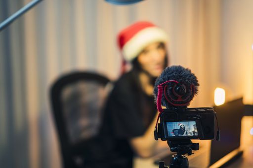 A selective focus shot of a young lady doing a video blog shooting wearing a Christmas hat