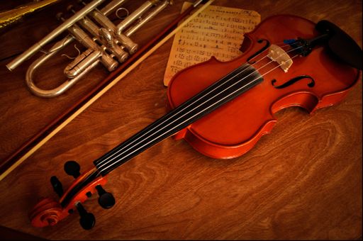 A closeup shot of old notes, violin, and a trumpet on wooden background