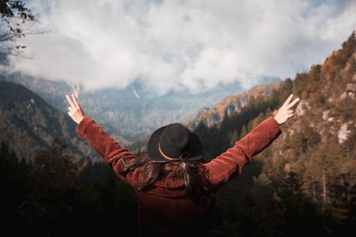 A beautiful shot from behind of a woman overlooking a mountainous landscape