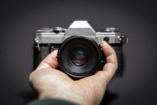 A selective focus closeup of a hand holding a camera on a black background