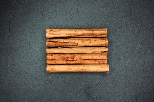 A high angle closeup shot of lined up cinnamon sticks on a black surface