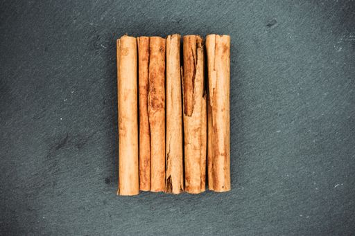 A high angle closeup shot of lined up cinnamon sticks on a black surface