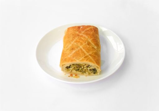 A high angle shot of a homemade healthy fresh tasty vegetable roll on a plate isolated on a white background. It is a puff dough filled with chard