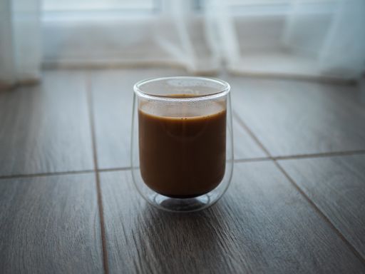 A closeup of fresh coffee in a double wall glass cup on a table
