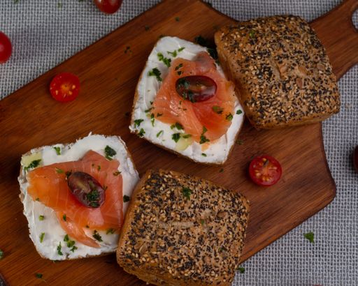 A high angle shot of delicious smoked salmon and cream cheese bagels, on a wooden cutting board