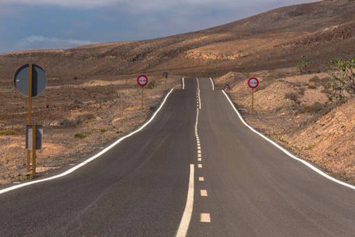 A winding road through the dunes of Corralejo desert with the volcano in the background, in Fuerteventura, Canary Islands, Spain
